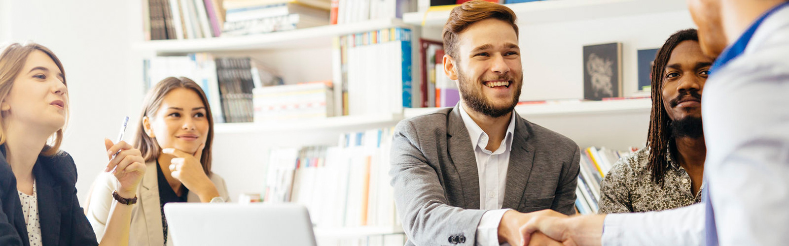 Adult students in a computer lab, one of them shaking hands with an instructor