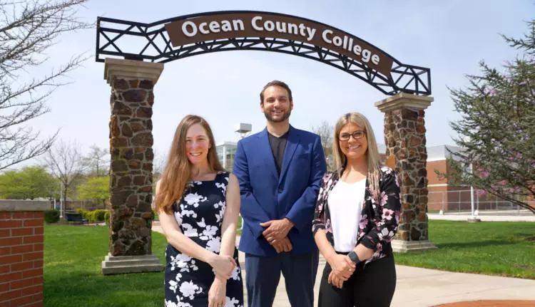 alumni Laura Wagner, Joe Mercadante, and Lisa Wit standing in from of the Ocean County College archway