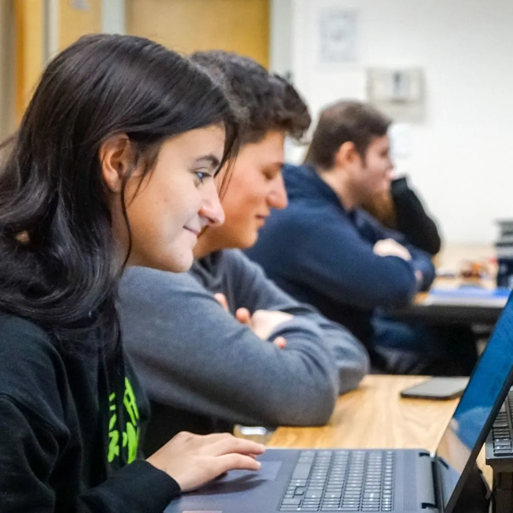 Students in class, focus on a female student on her laptop