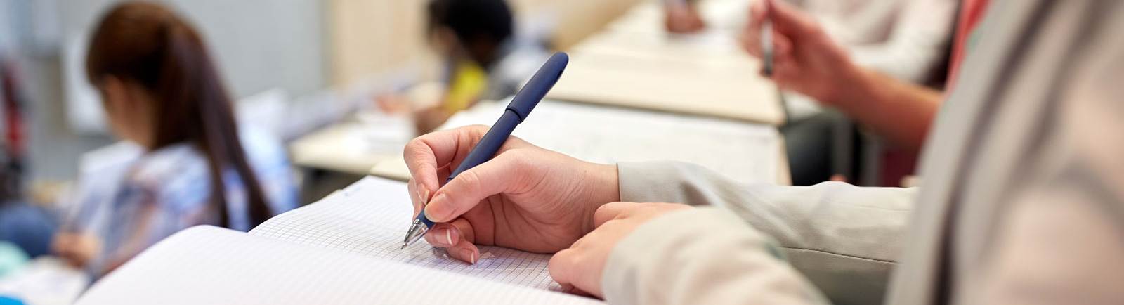 Close up of a person writing in a notebook.