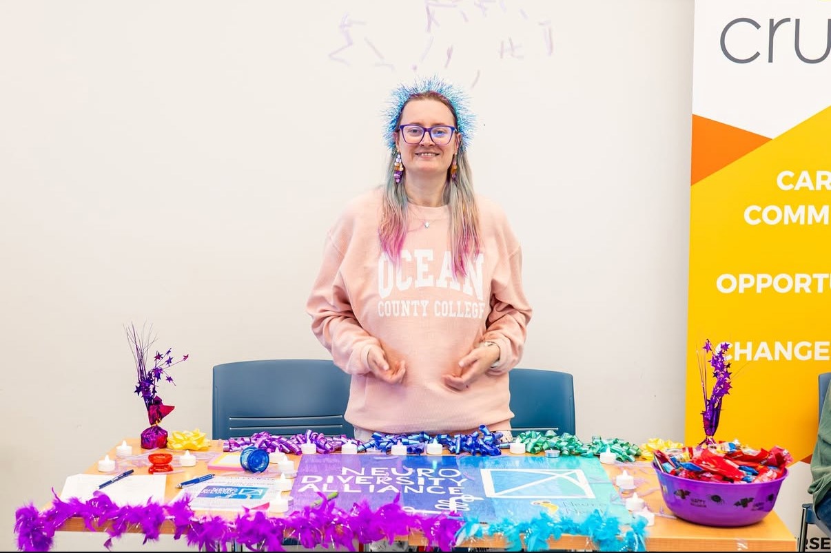 Student wearing an OCC Sweatshirt in front of a table at the club fair. 